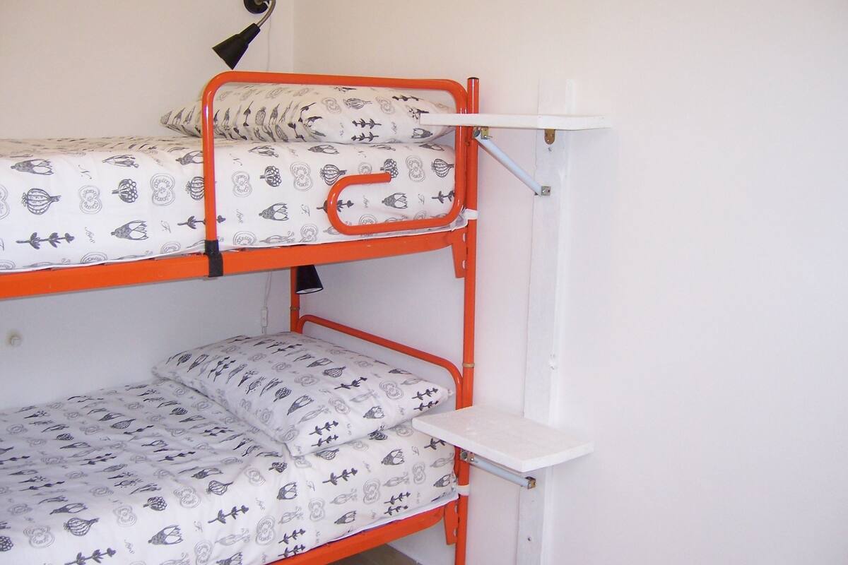 Een stapelbed met twee verhoogingen, elk met een matras en kussens met een patroon.