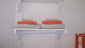 A white, rustic shelf with folded towels in grey and orange. - Casa Cairo Affittacamere (Mombaroccio)