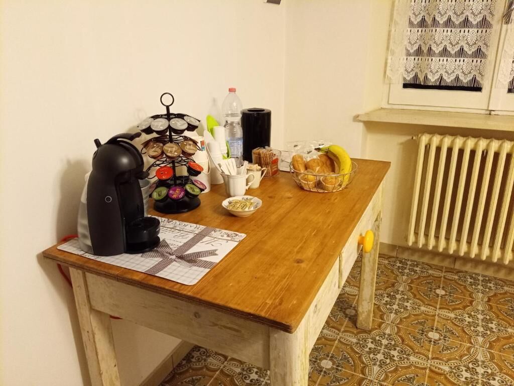 A kitchen counter with a coffee maker, a fruit basket, and a radiator.