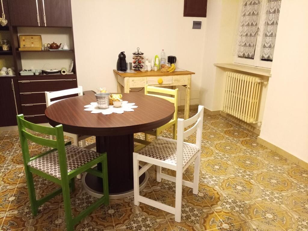 A dining area with a round table, two chairs, a radiator, and patterned floor tiles.