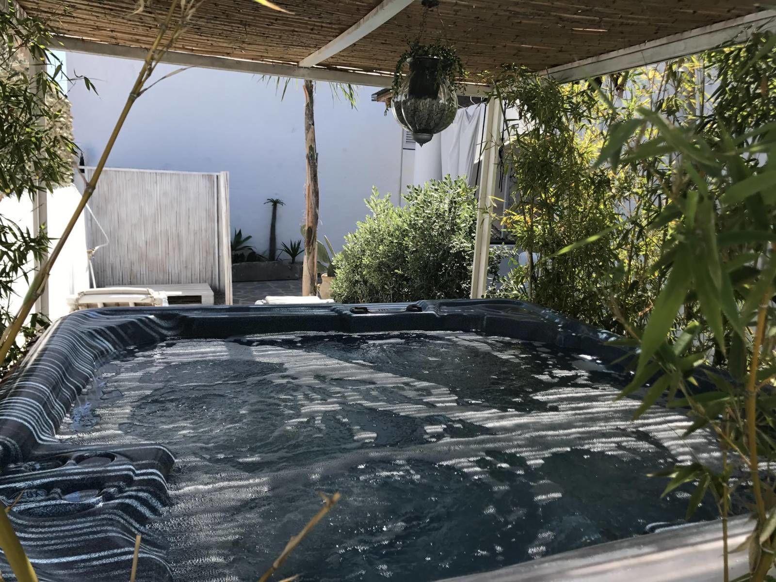Ein Whirlpool mit strukturierter Oberfläche, umgeben von Bambuspflanzen und einer Pergola.