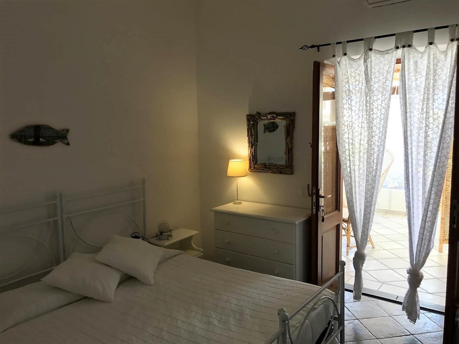 Ein Schlafzimmer mit Bett, Nachttisch, Lampe, Kommode und einer Fischdekoration an der Wand.