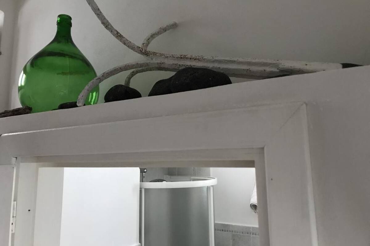 A white shelf with a green bottle and a branch.