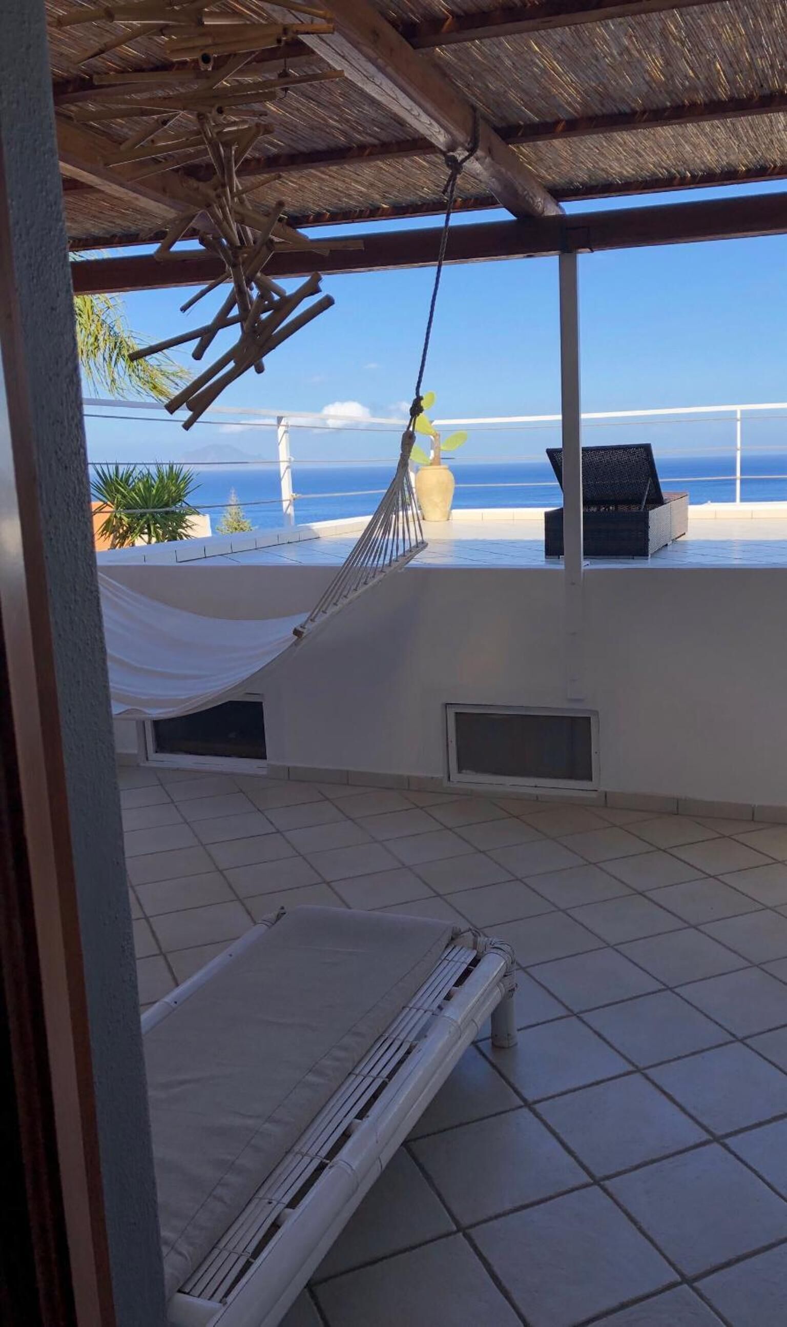 Un hamac et un lit sur un balcon avec vue sur l’océan.