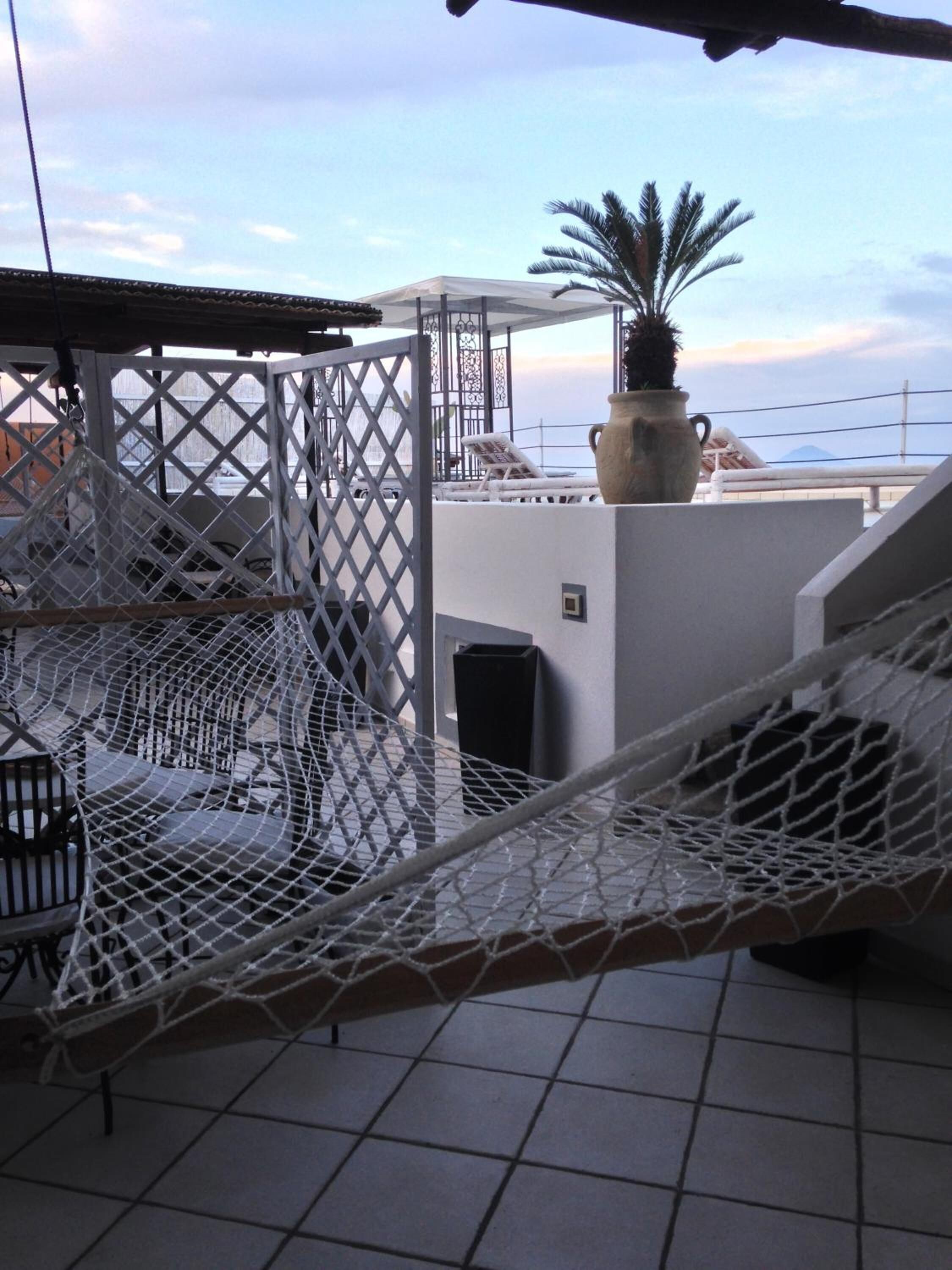Una terraza en la azotea con una hamaca, una planta en maceta y vistas al mar.