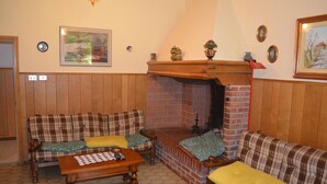 A cozy living room with a fireplace, plaid sofas, and a wooden coffee table. - Albergo Padellino (Vaglia)