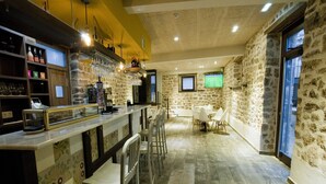 Una zona de bar con pared de piedra, taburetes y mostrador con caja registradora.