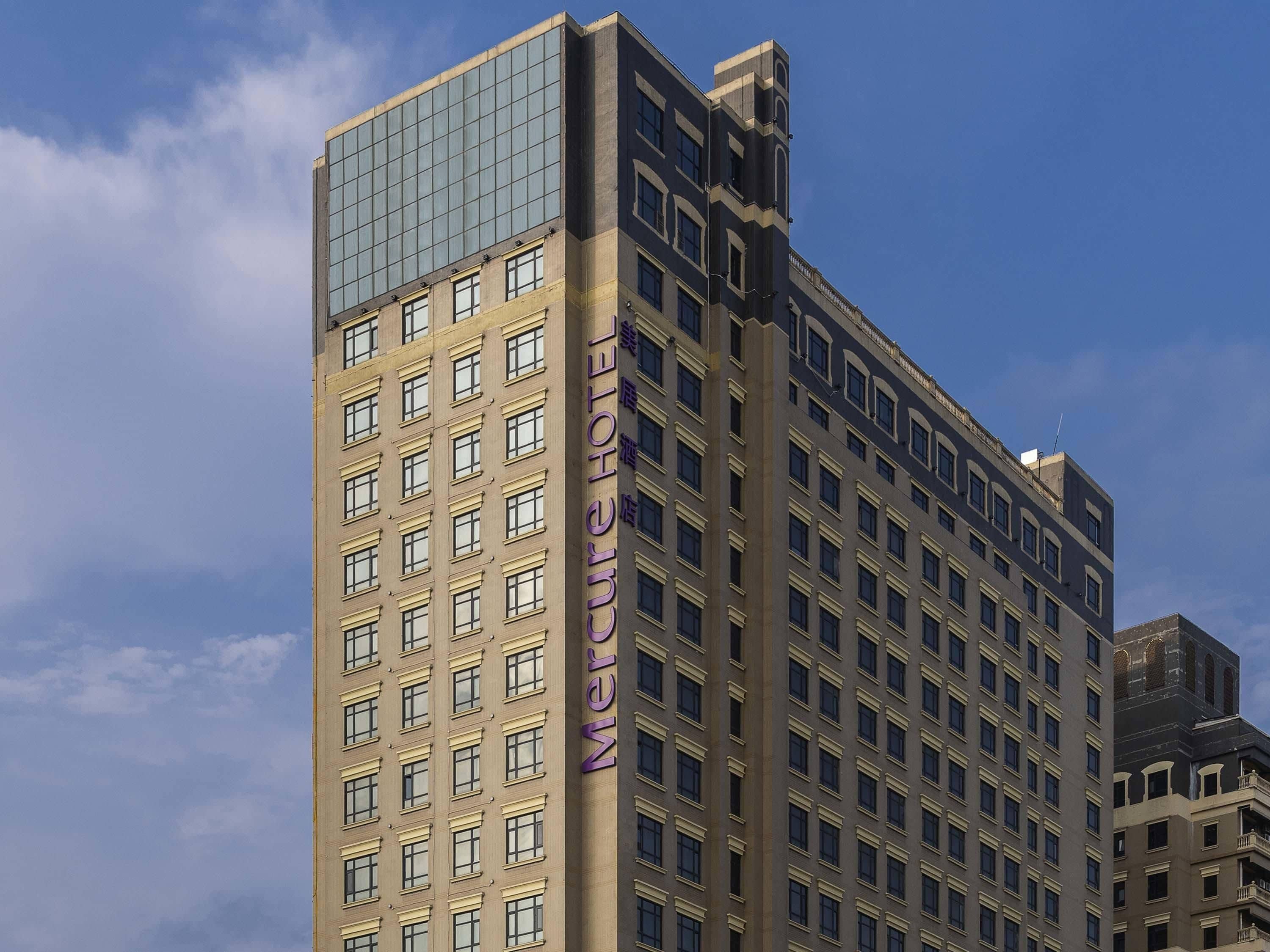 Un edificio de hotel alto con un llamativo letrero vertical que dice 'Mercure Hotel'.