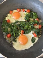 Una sartén con huevos y verduras.