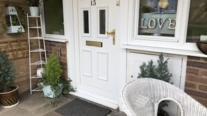 A white door with the number 15, a white wicker chair, and a small Christmas tree. - Love & Peace (Orpington)