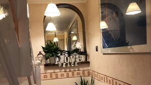 A hotel hallway with a 'Welcome' sign, a 'Love & Peace' sign, and a potted plant. - Love & Peace (Orpington)