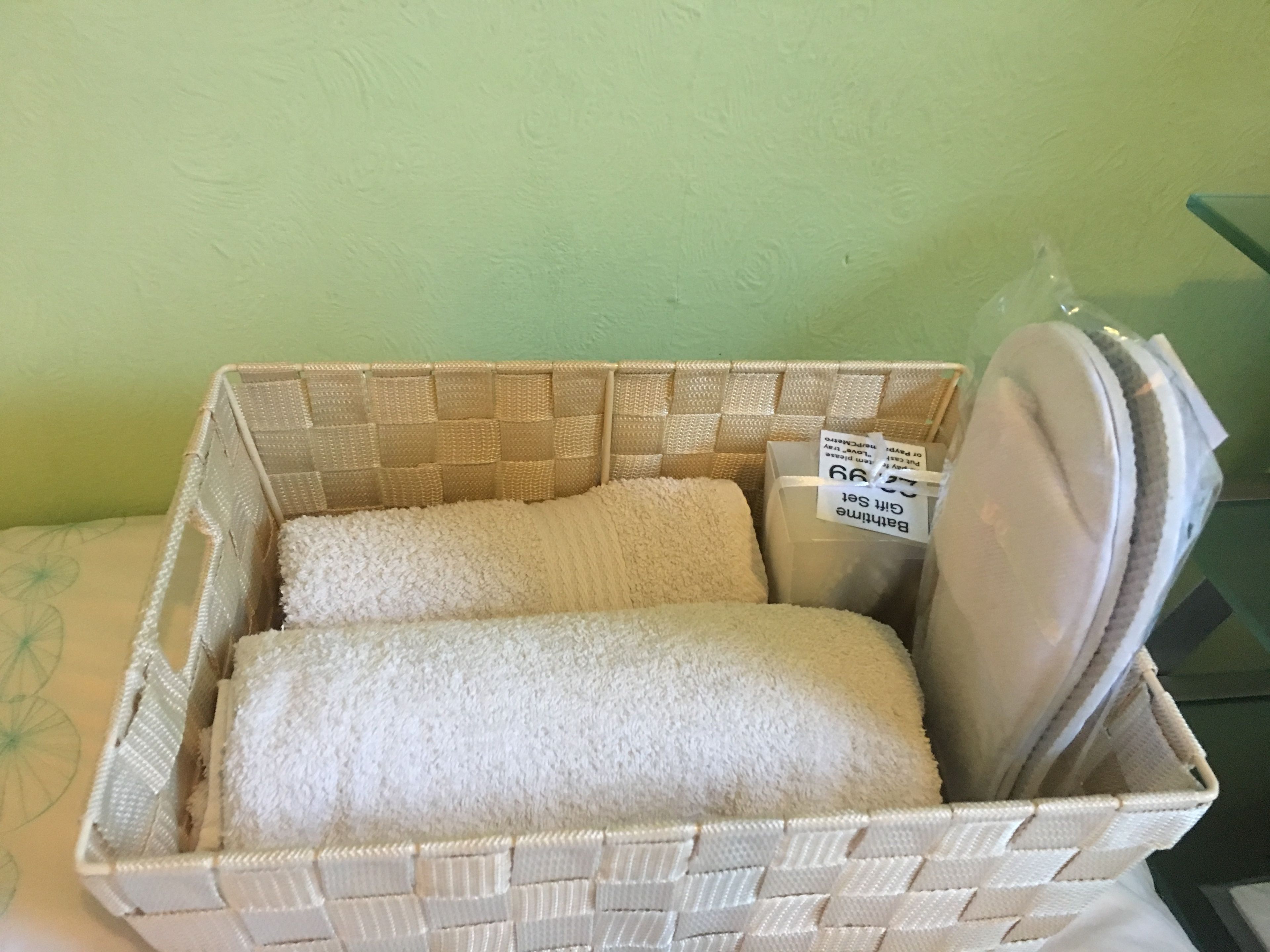 A wicker basket with a tag labeled "Bathing Suit" containing a white towel.
