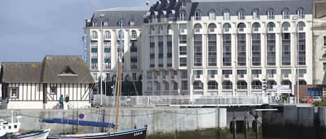 A historic building with a large facade, a dock with a boat, and a small adjacent structure.
