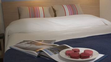 Un lit bien fait, avec un magazine et une assiette de macarons.