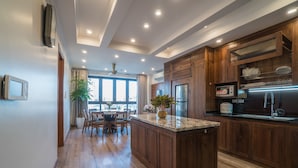 A modern kitchen with wooden cabinets, a granite countertop, and a built-in oven. - iRest Apartment (Hanoi)