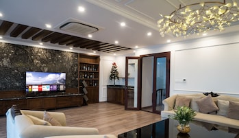 Uma sala de estar moderna com televisão de tela plana, prateleiras de madeira, uma árvore de Natal e uma mesa de centro de vidro.