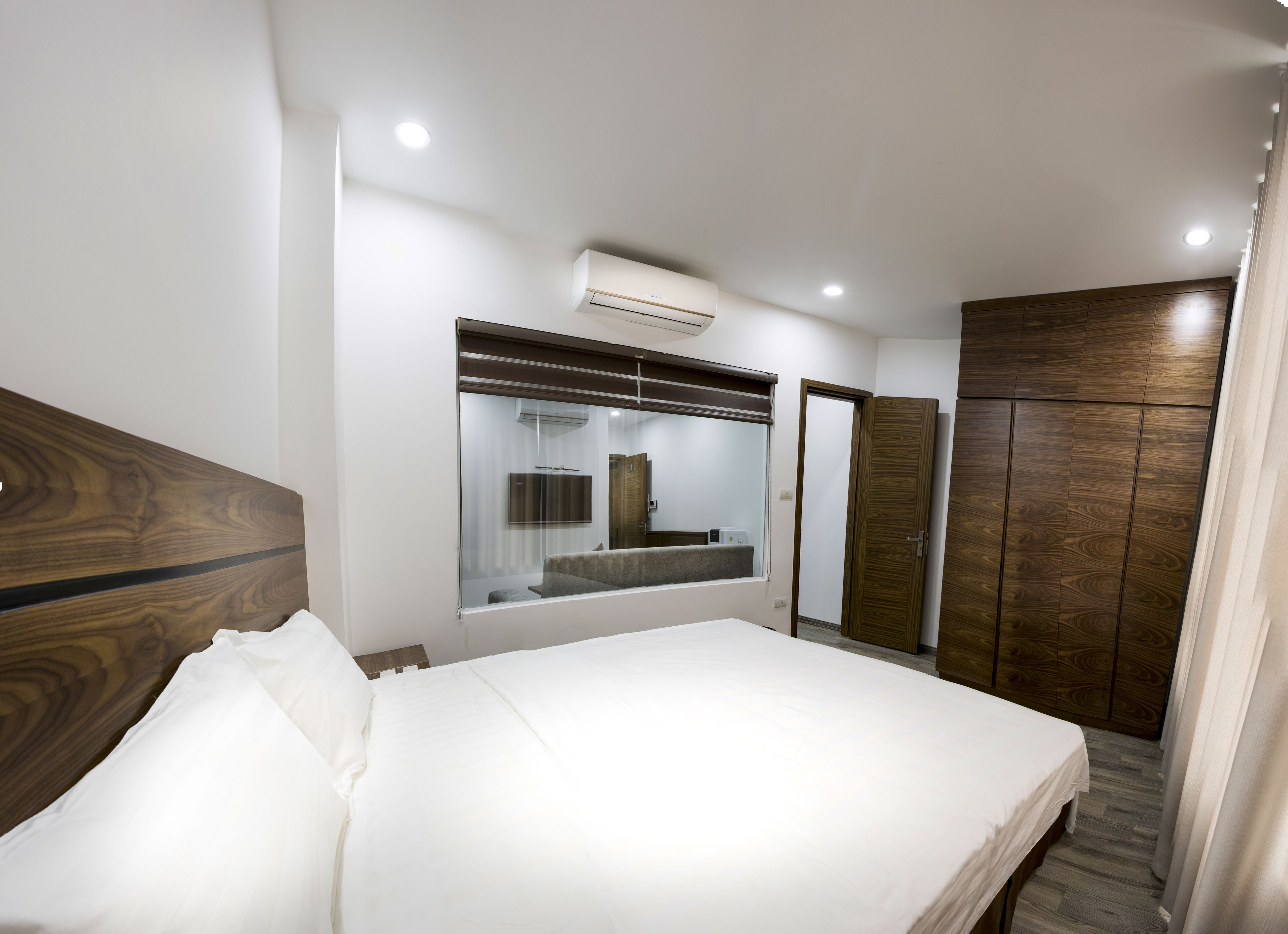 Une chambre d’hôtel avec un grand lit, une armoire, un miroir et un appareil de climatisation.
