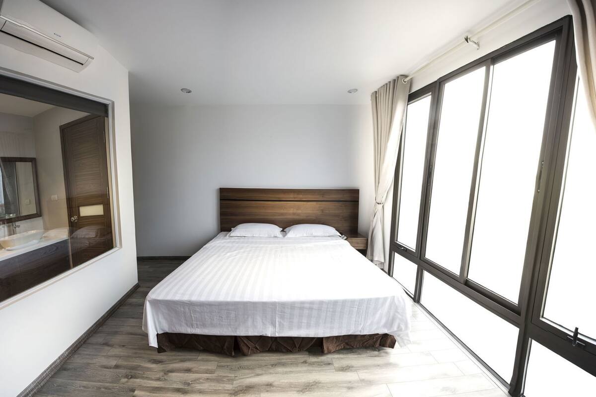A bedroom with a large bed, a mirror, and a window.