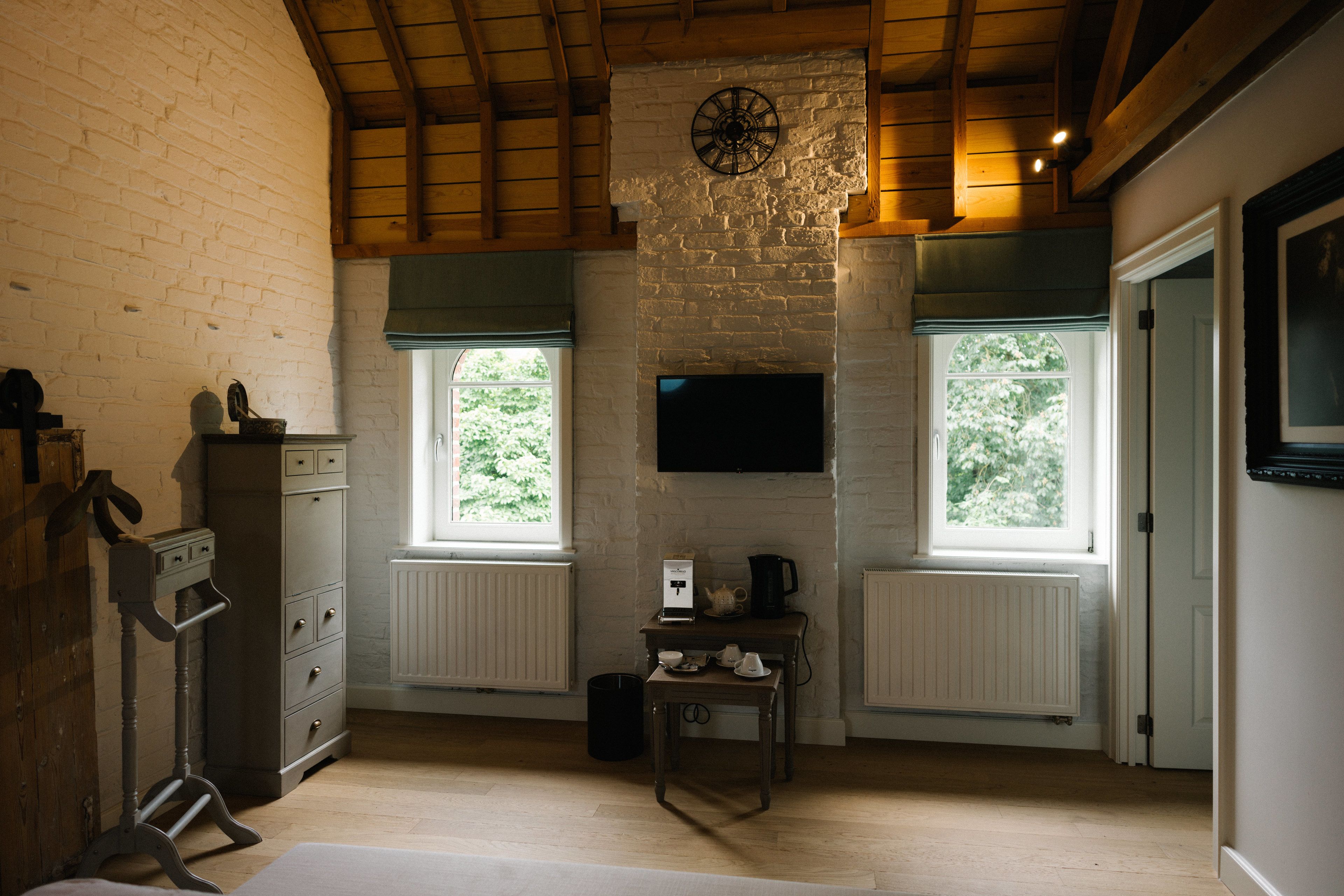 A room with a fireplace, a clock, and a television on the wall.