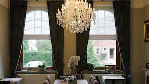 Comedor con candelabro, ventanas amplias y vista a la vegetación exterior.
