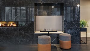 A modern lobby with a fireplace, seating area, and two ottomans. - Residence Inn by Marriott Frankfurt City Center (Frankfurt)