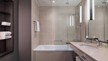 A modern bathroom with a glass-enclosed shower, a bathtub, and a vanity with a sink.