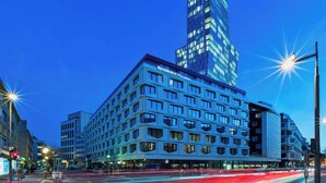 A modern hotel with a prominent 'Residence Inn' sign, featuring a multi-story structure with a mix of rectangular and arched windows, and a high-rise building in the background. - Residence Inn by Marriott Frankfurt City Center (Frankfurt)