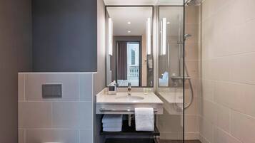 A modern bathroom with a glass-enclosed shower, a sink with a mirror, and a toilet.