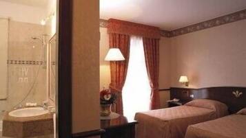 Una camera d'albergo con bagno, un letto, un comodino e una lampada.