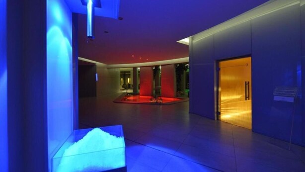 Un moderno vestíbulo de hotel con una fuente central, una zona de recepción y una vitrina de vidrio.