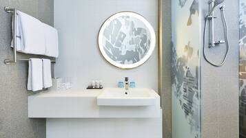 A modern bathroom with a white sink, a round mirror, and a shower with a glass door.