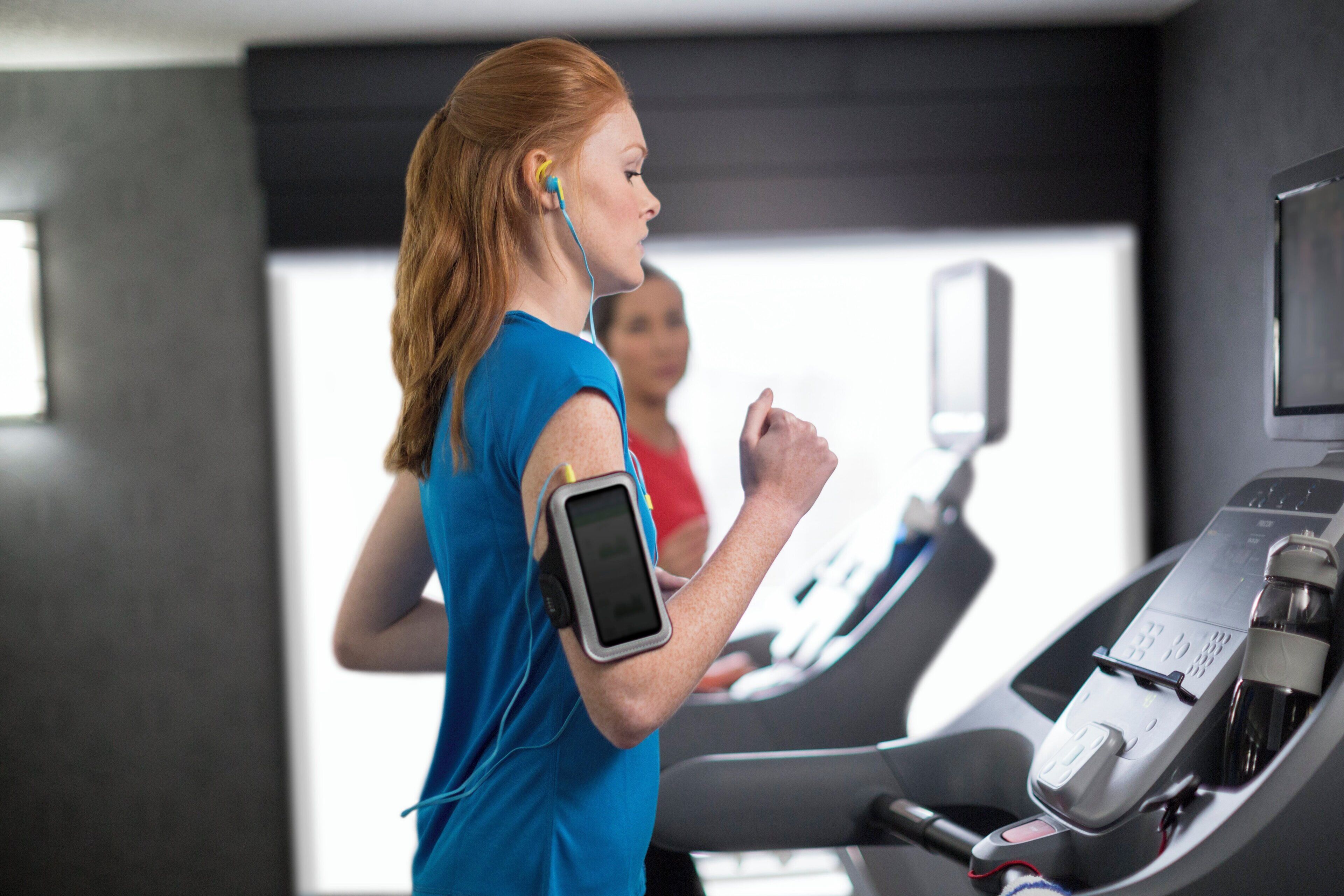 A person using a treadmill in a gym with a digital display and a water bottle on the side.