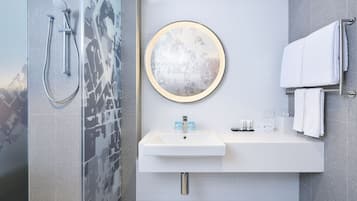 Een moderne badkamer met een douche, wastafel en handdoekrek.