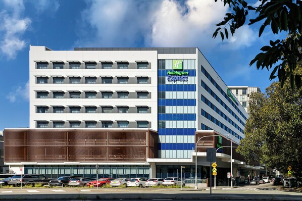 A Holiday Inn Express hotel with a modern facade, multiple floors, and a parking lot in front. - Holiday Inn Express Newcastle by IHG (Newcastle West)