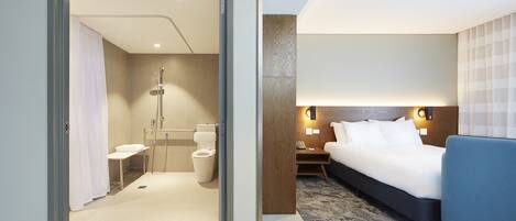 Una habitación de hotel moderna con ducha, inodoro y una cama con una silla azul.