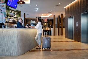 A reception area with a counter, a digital screen, and a wall-mounted plant. - Holiday Inn Express Newcastle by IHG (Newcastle West)