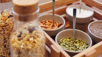 A wooden tray containing various food items including granola, nuts, and seeds.