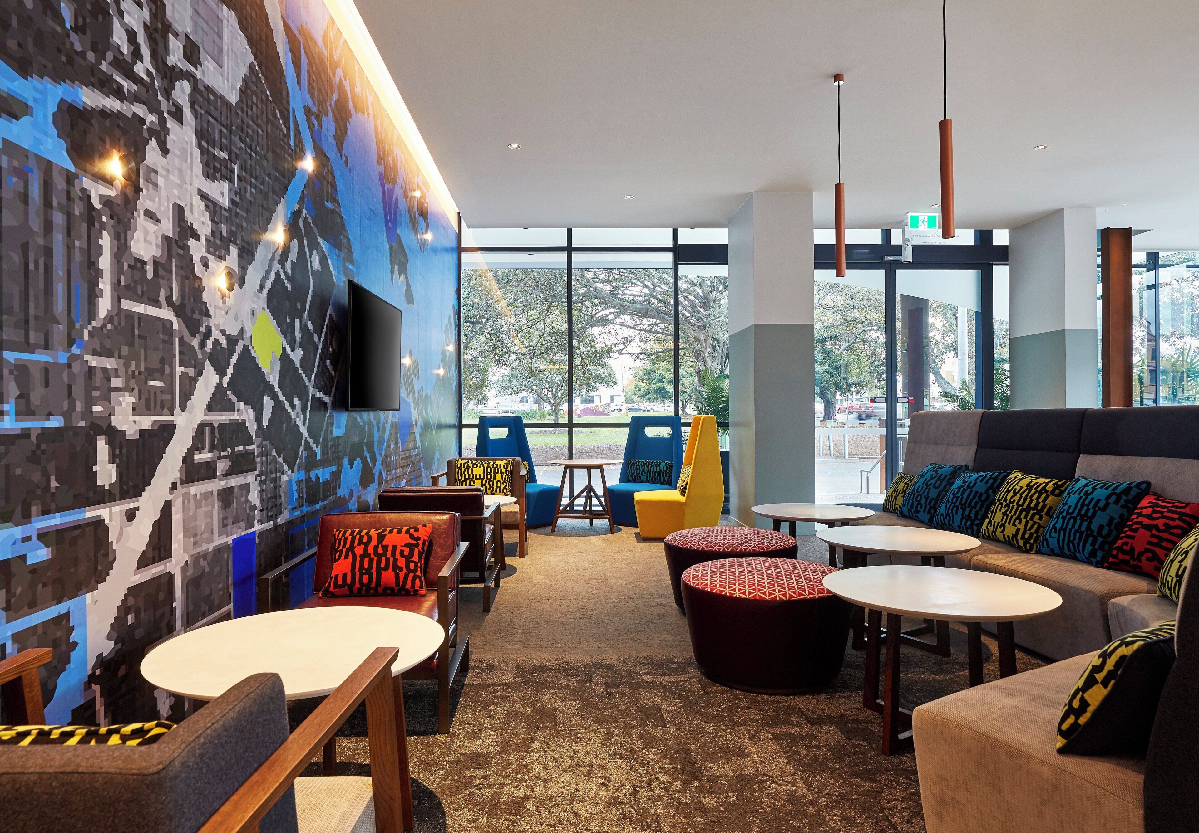 Een modern interieur met zitopstellingen, een groot raam en een aan de muur bevestigde televisie.