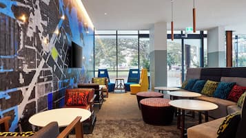 Een modern interieur met zitopstellingen, een groot raam en een aan de muur bevestigde televisie.