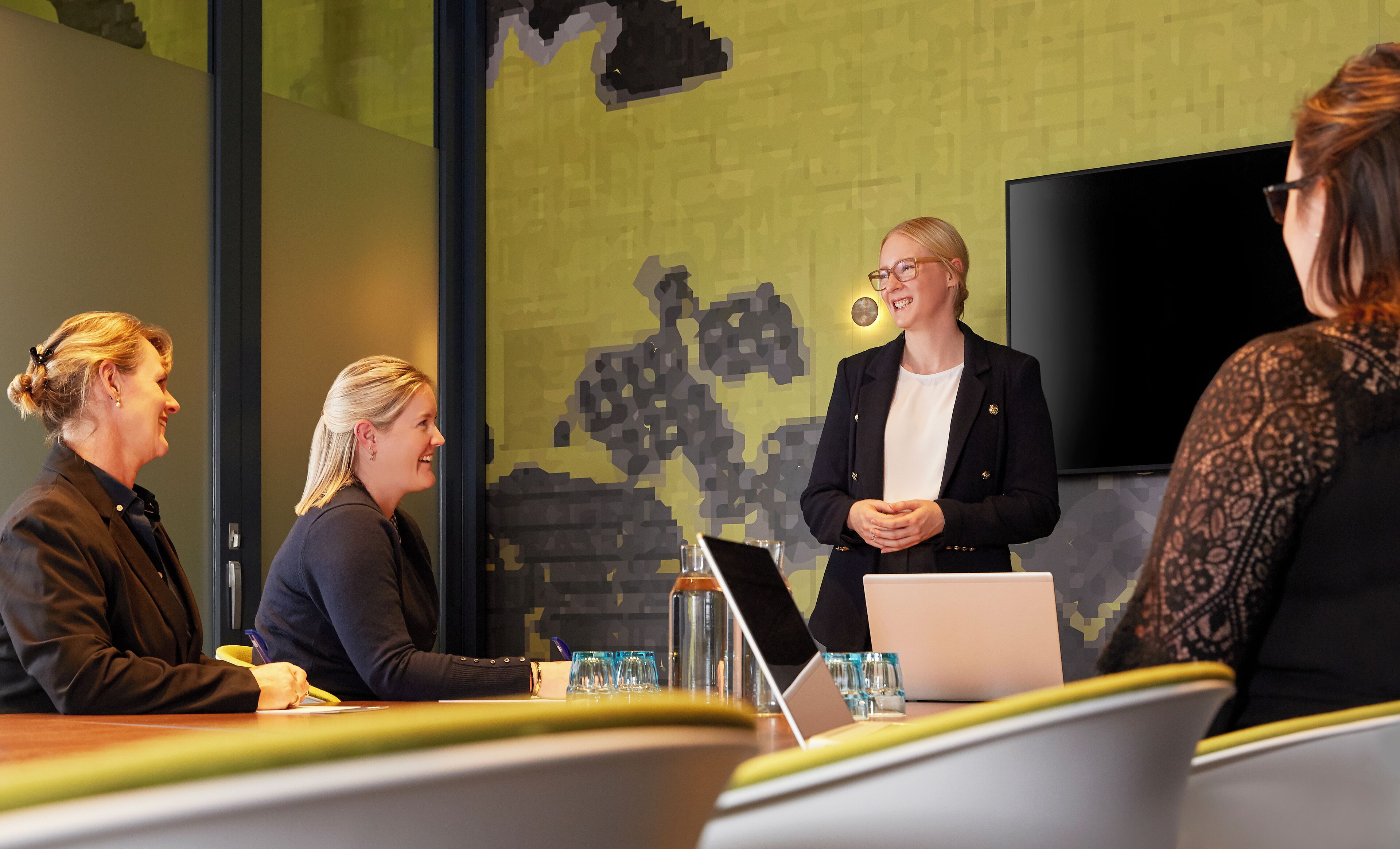 A conference room with a large screen, a laptop, and a water bottle on the table.