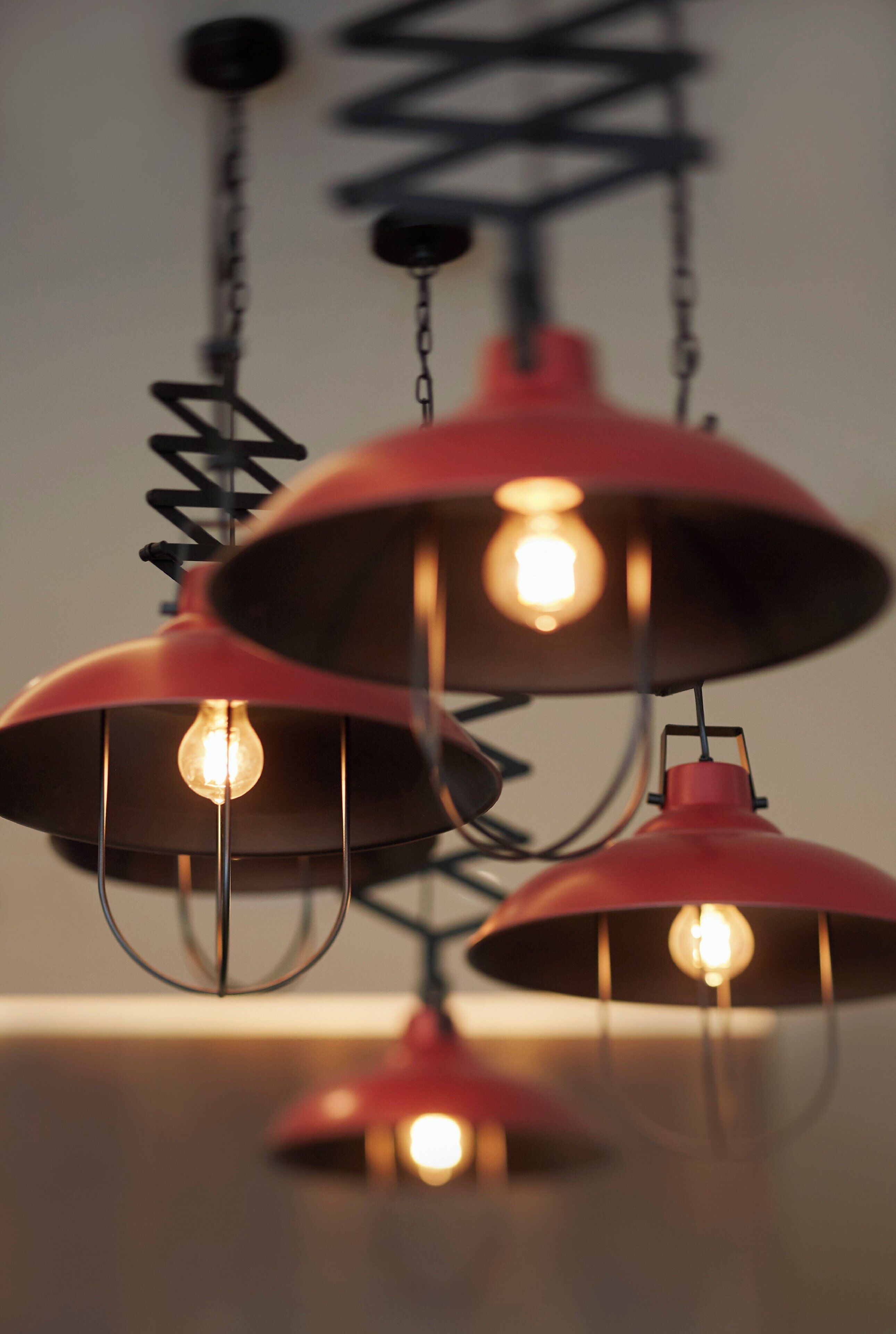 A series of red pendant lights with exposed bulbs, hanging from a metal structure.