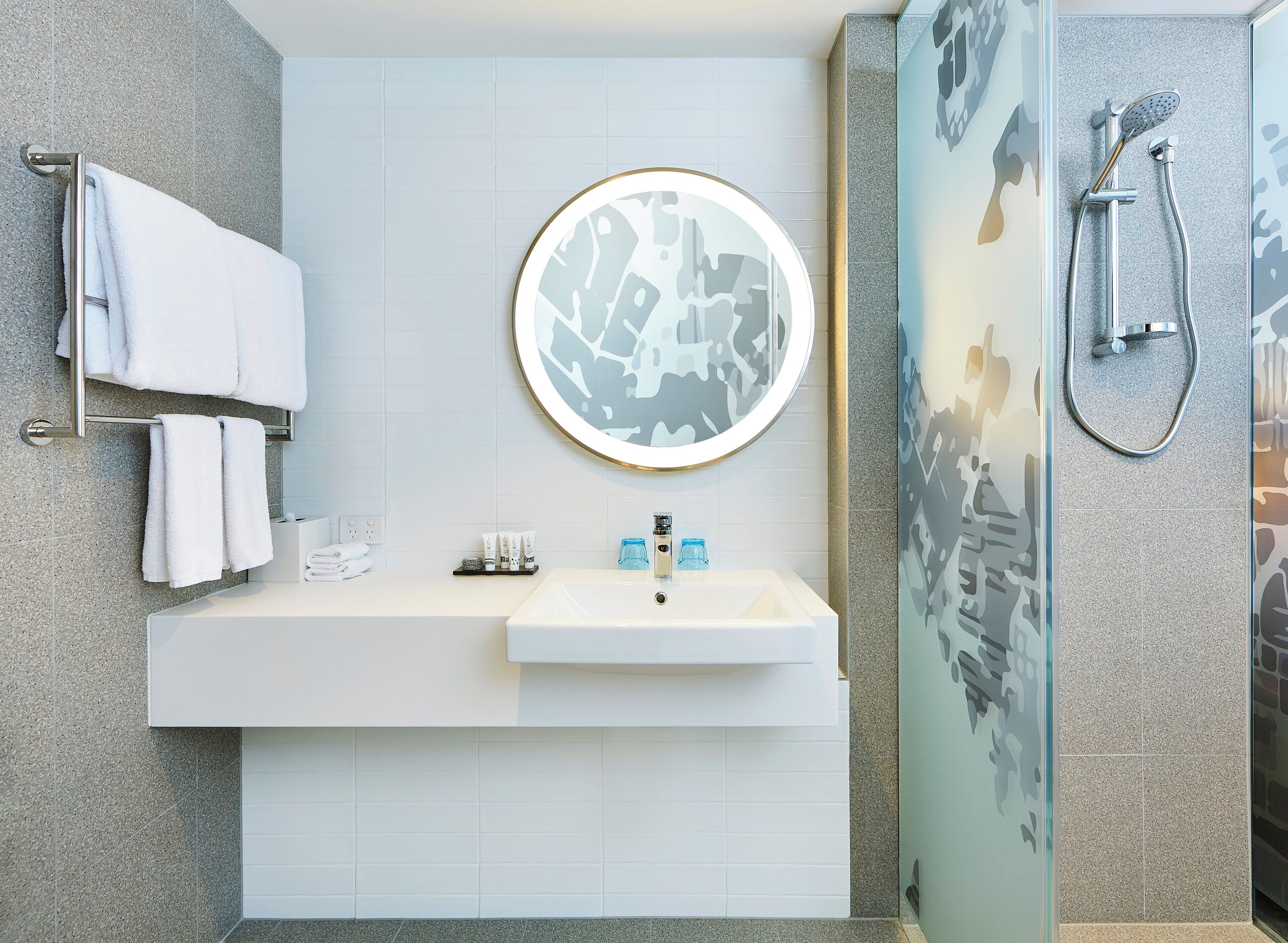 Une salle de bain moderne avec un lavabo, un miroir et une douche.