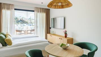 Hotelkamer met een bed, een eettafel, twee stoelen, een televisie en uitzicht op een stadsgezicht.
