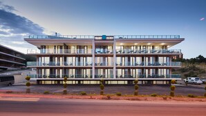 A modern multi-story hotel with balconies, large windows, and a parking area. - Lisi Hills Hotel (Tbilisi)
