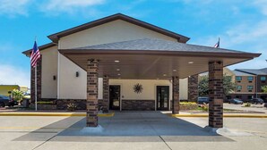 A hotel entrance with a covered patio, American flags, and a sunburst decoration. - Quality Inn Galesburg Near US Highway 34 and I-74 (Galesburg)