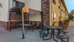 An outdoor patio with a covered seating area, a table, and a grill. - Quality Inn Galesburg Near US Highway 34 and I-74 (Galesburg)