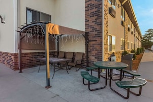 An outdoor patio with a covered seating area, a table, and a grill.