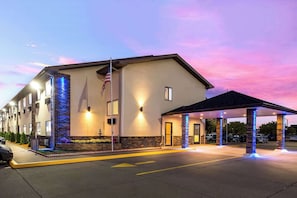 A hotel with a covered entrance, a flagpole with an American flag, and a parking lot. - Quality Inn Galesburg Near US Highway 34 and I-74 (Galesburg)