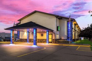 A hotel with a covered entrance, a flag, and a sign indicating a Q rating.