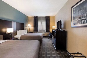 A hotel room with two beds, a desk, a television, and a cityscape painting. - Quality Inn Galesburg Near US Highway 34 and I-74 (Galesburg)